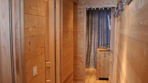 Un pasillo de madera con un banco, paredes de madera y una puerta que da a otra habitación.