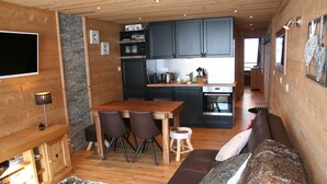 Un interior acogedor con un comedor de madera, un sofá y una cocina con armarios oscuros y salpicadero de azulejos.