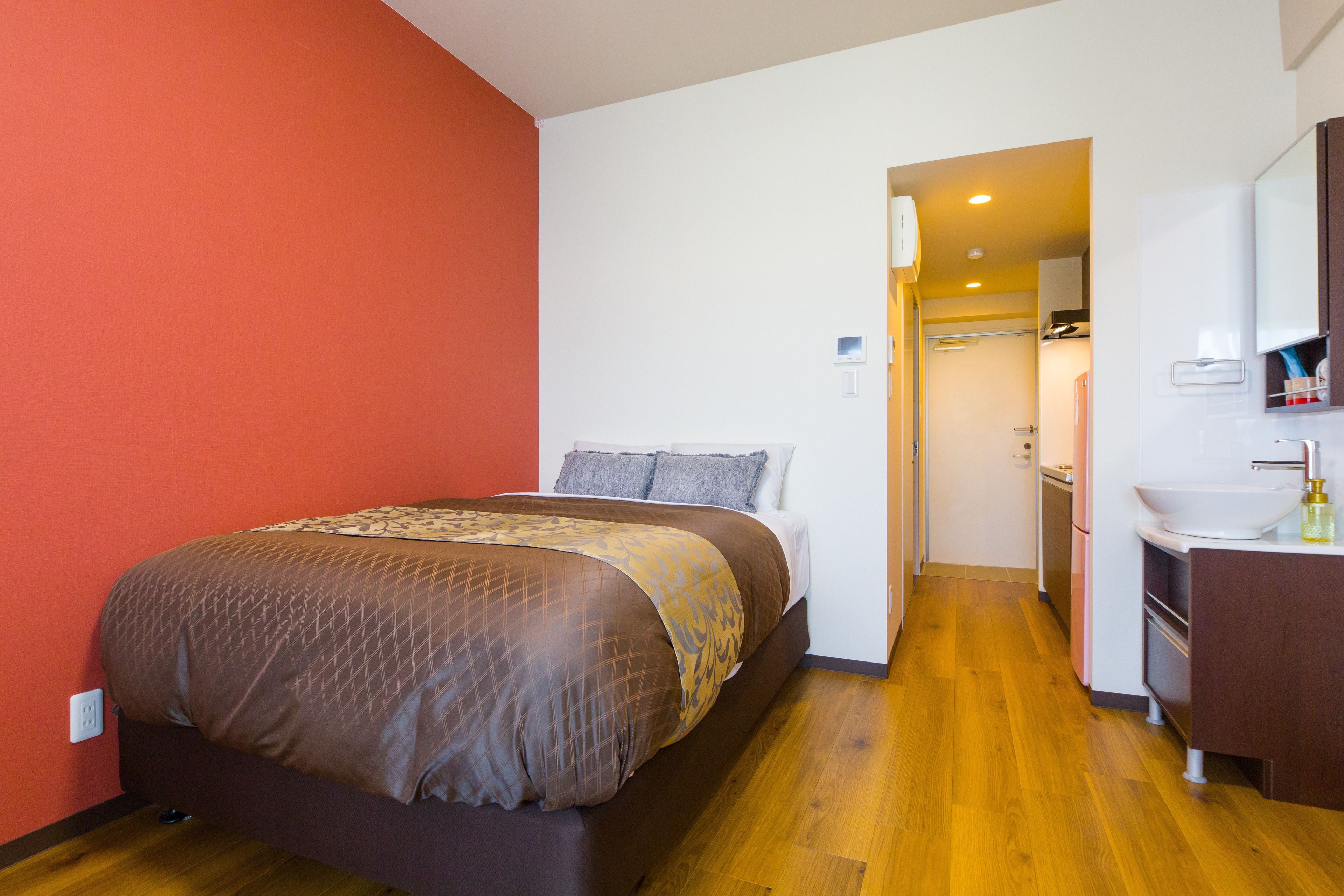 A hotel room with a bed, a bathroom with a sink, and a door leading to another room.