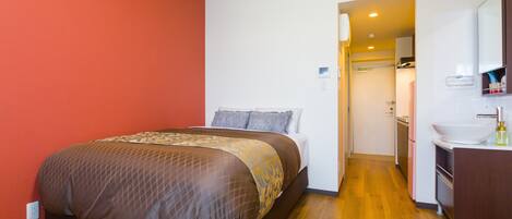 A hotel room with a bed, a bathroom with a sink, and a door leading to another room.