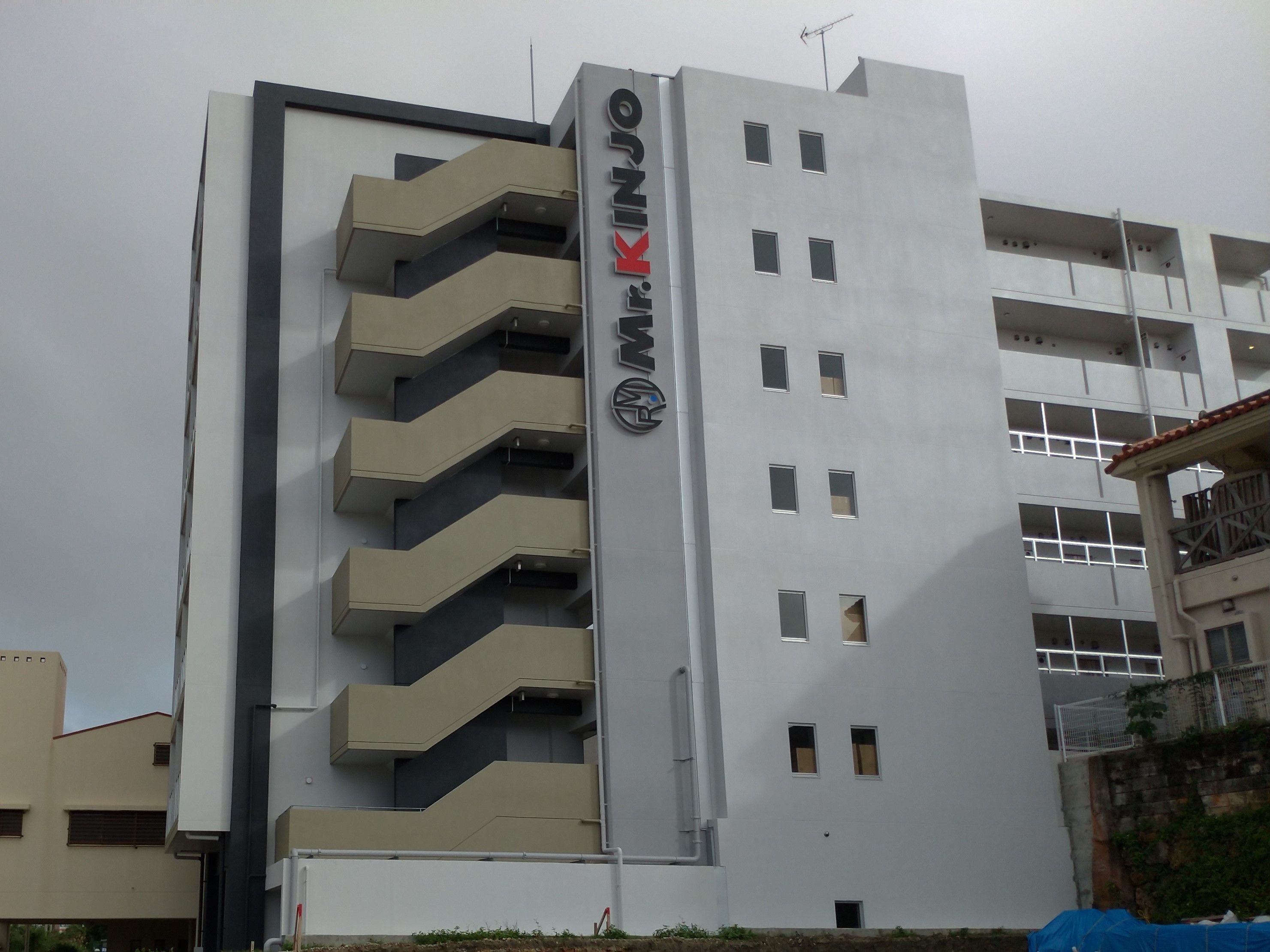 Un bâtiment moderne dont la façade est ornée d’une enseigne bien visible portant le nom « Max KINJO ».