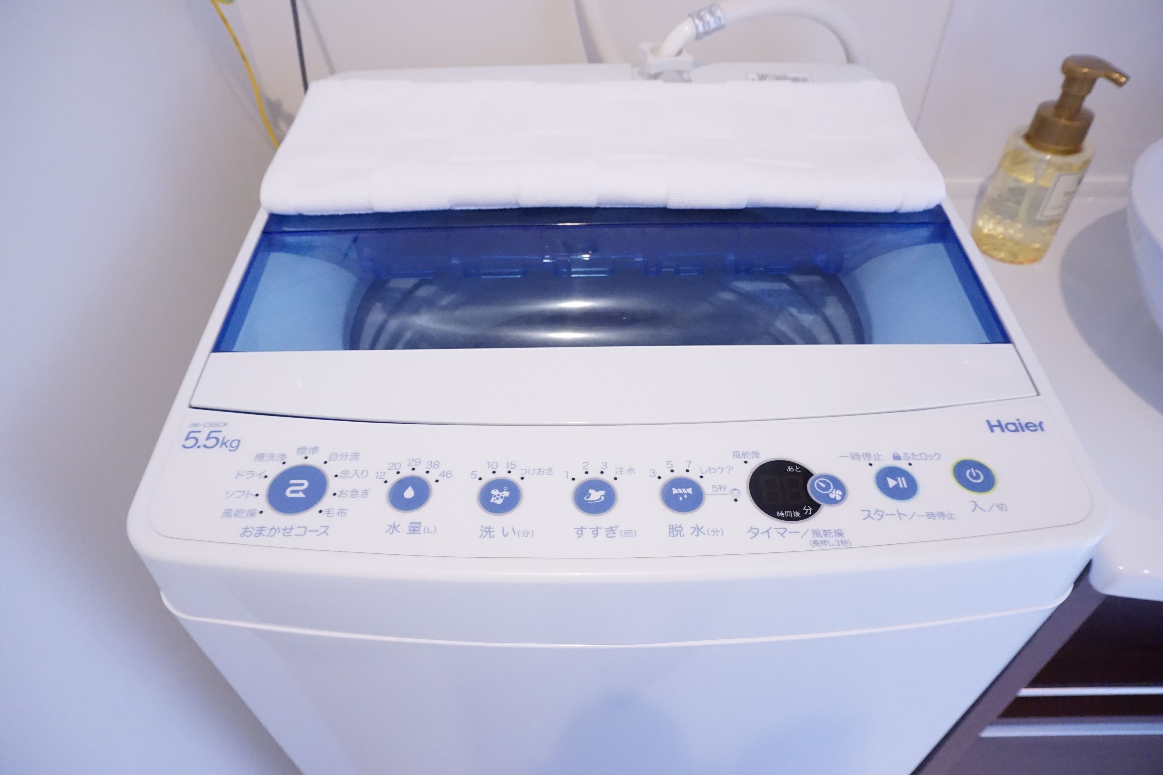 A white Haier washing machine with a blue interior, a white top, and a control panel with Japanese text.