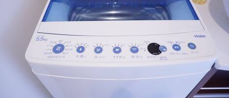 A white Haier washing machine with a blue interior, a white top, and a control panel with Japanese text.