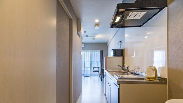 Ett modernt kök med diskho, mikrovågsugn och brödrost. I bakgrunden syns en matplats med ett bord och stolar.