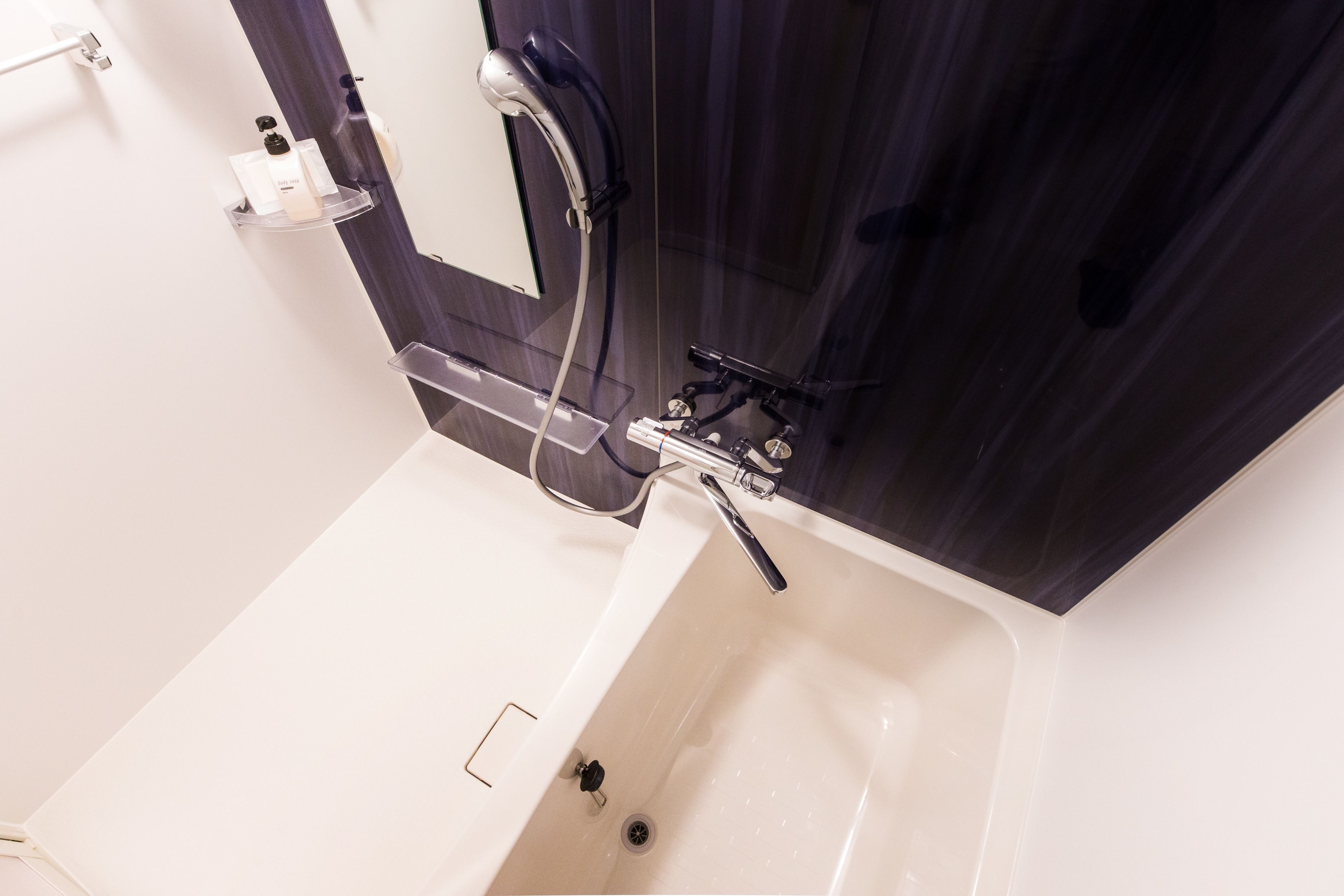 Un baño con una bañera blanca, ducha y espejo.