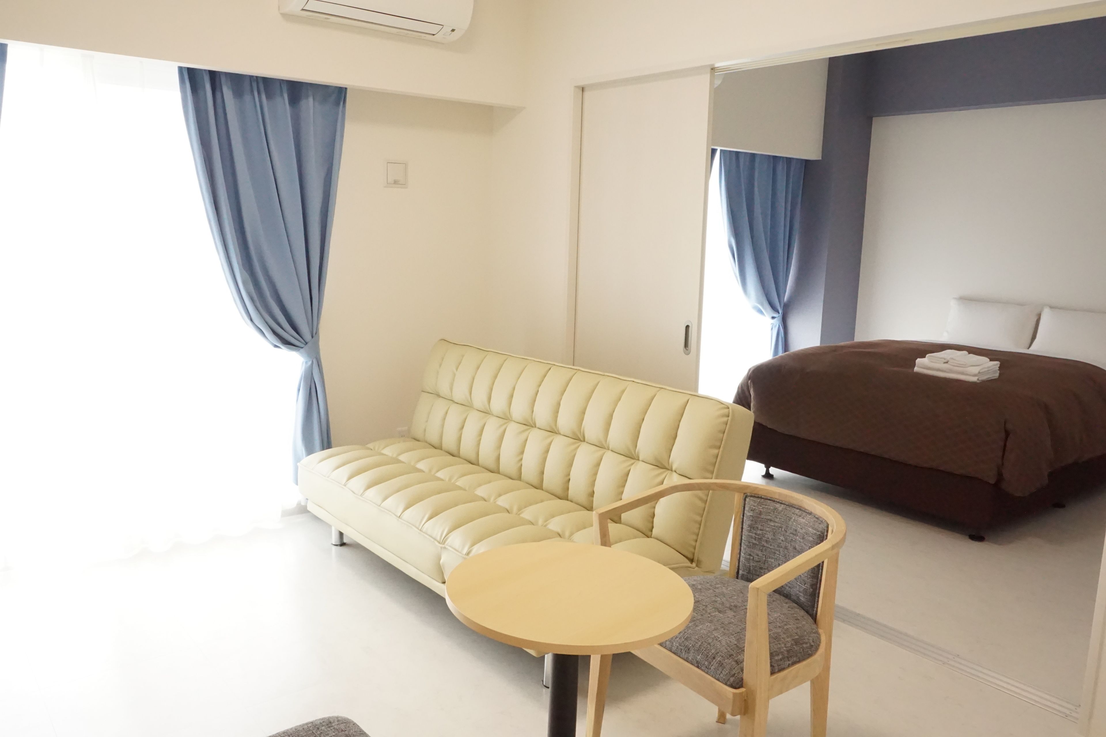 Una habitación de hotel moderna con sofá, una mesita redonda, cama y sillón.