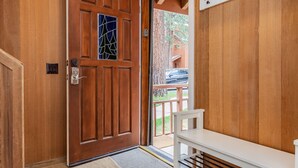 Une porte en bois ornée d’un vitrail, un banc blanc et une rambarde en métal à l’extérieur.