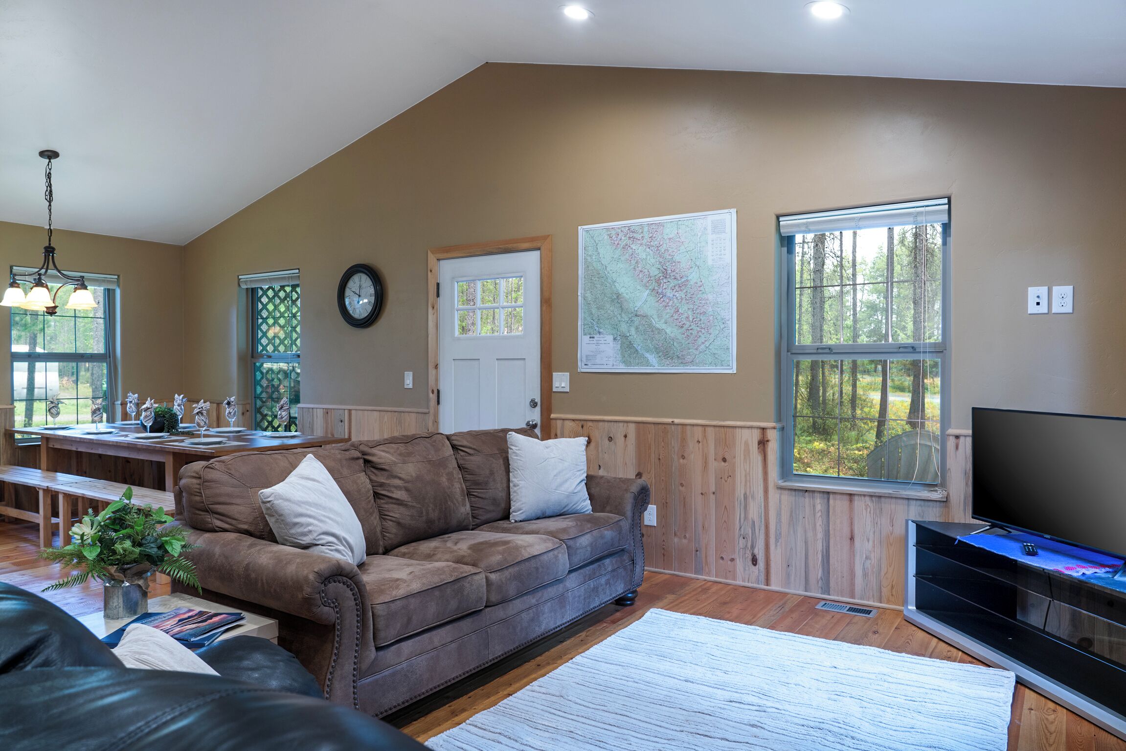 A living room with a brown couch, a dining table, and a TV.