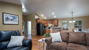 Ein geräumiges Wohnzimmer mit einer schwarzen Ledersofa und einem braunen Sofa, Holzboden und einem gerahmten Bild an der Wand.