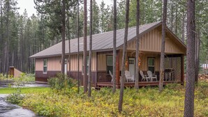 Eine Hütte mit Veranda, Sitzgelegenheiten im Freien und Blick auf den umliegenden Wald.
