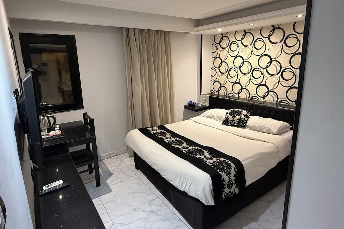 A modern bedroom with a large bed, a desk, and a mirror.