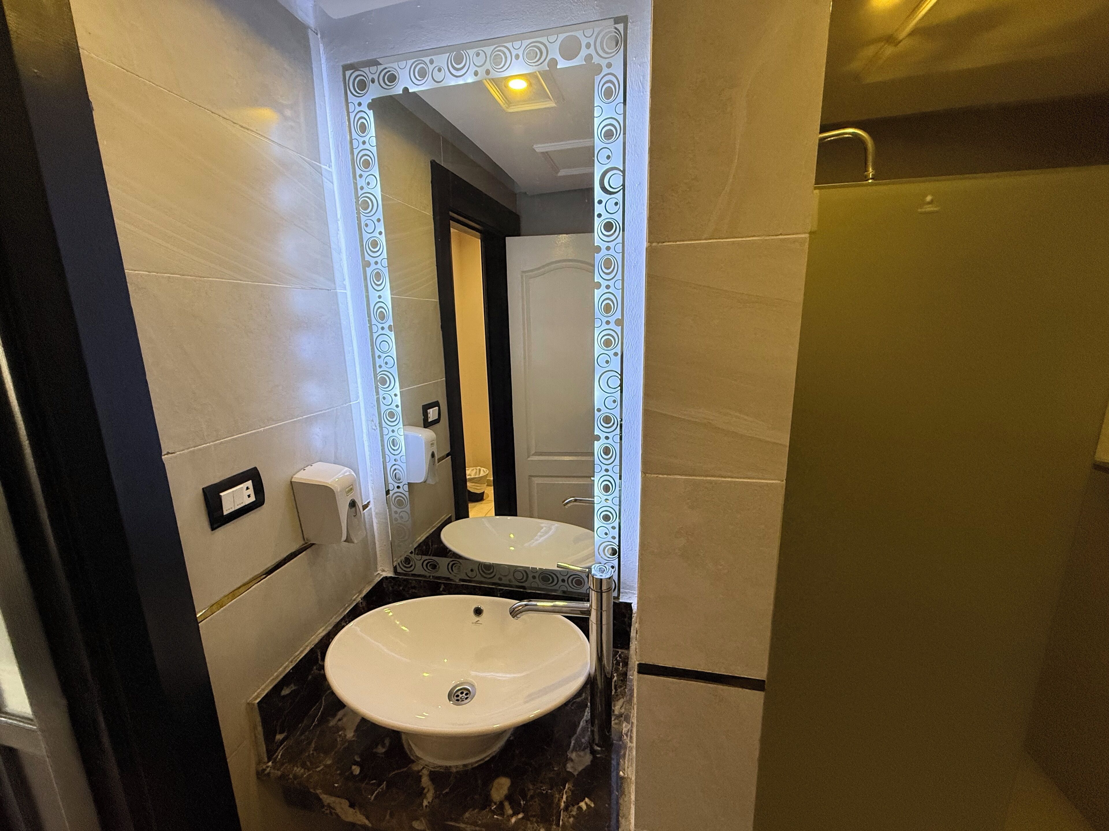 A bathroom with a white sink, a mirror with a decorative frame, and a shower area.