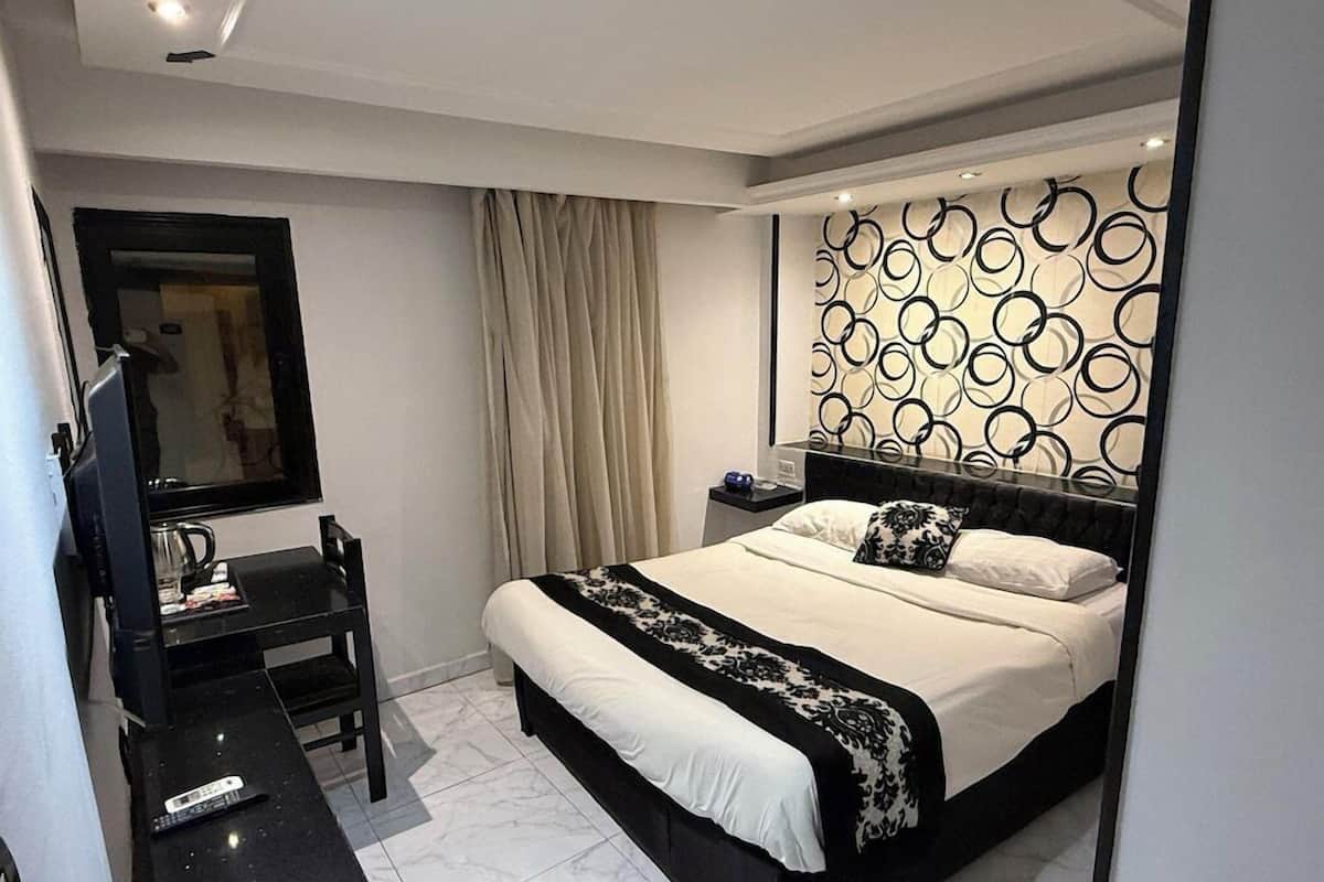 A modern bedroom with a large bed, a desk, and a mirror.
