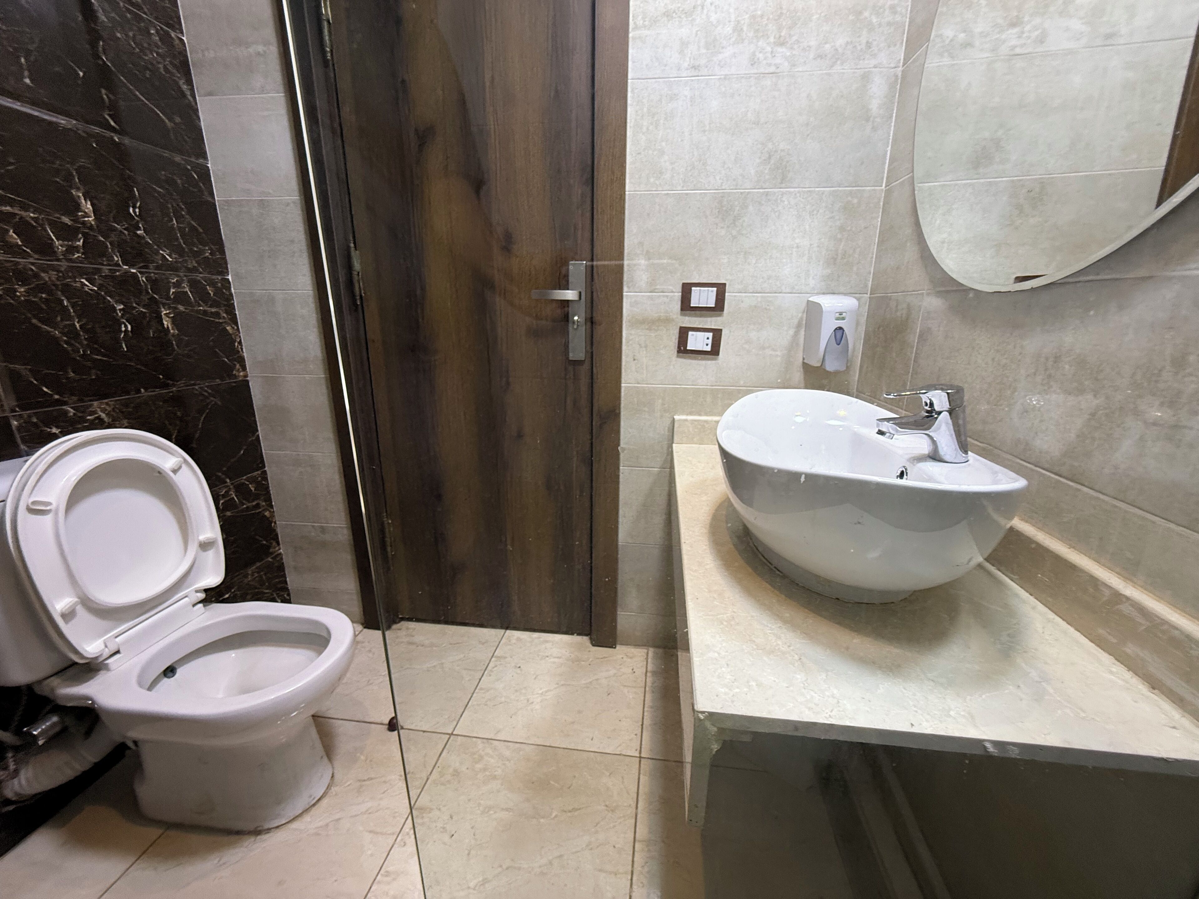 Un baño con inodoro, lavamanos y puerta de madera.