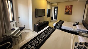 Habitación de hotel con dos camas, un escritorio, una silla, un televisor y un equipo de aire acondicionado.