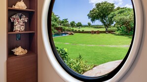 Una habitación con ventanal circular que ofrece vistas a un jardín y árboles.