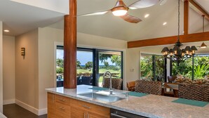Una cocina moderna con una isla grande, vigas de madera y vistas al exterior.