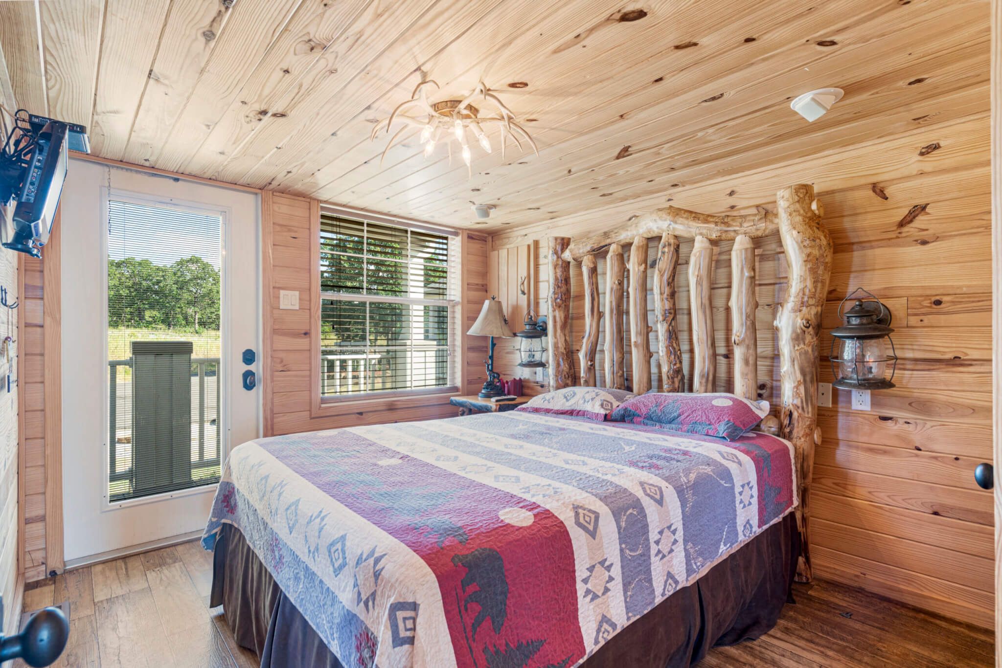 Un dormitorio acogedor con techo de madera, una cama grande con colcha colorida, una ventana con persianas y una decoración rústica en la pared.