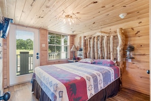 Un dormitorio acogedor con techo de madera, una cama grande con colcha colorida, una ventana con persianas y una decoración rústica en la pared.