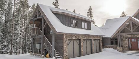A cabin with a stone exterior, wooden balcony, and a staircase leading to the entrance.