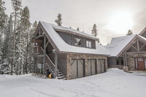 En stuga med en fasad av sten, en träbalkong och en trappa som leder upp till entrén.