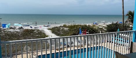 A poolside view with a beach in the background.