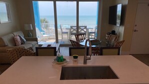 Una cocina con un amplio ventanal que da a un balcón y vistas a la playa.