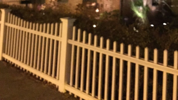 Um edifício de tijolos com várias janelas e uma cerca branca de piquete na frente.