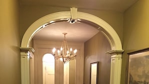 Corredor com carpete, um lustre, um radiador e um quadro na parede.