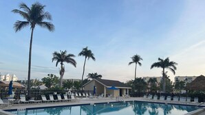 A swimming pool with lounge chairs and palm trees. - Welcome to Santa Maria 310, a little piece of Paradise! (Fort Myers Beach)