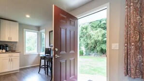 A kitchen with white cabinets, a dining area with a table and chairs, and a large window. - Private House in Woodinville with Hot Tub, close to Wineries! (Woodinville)