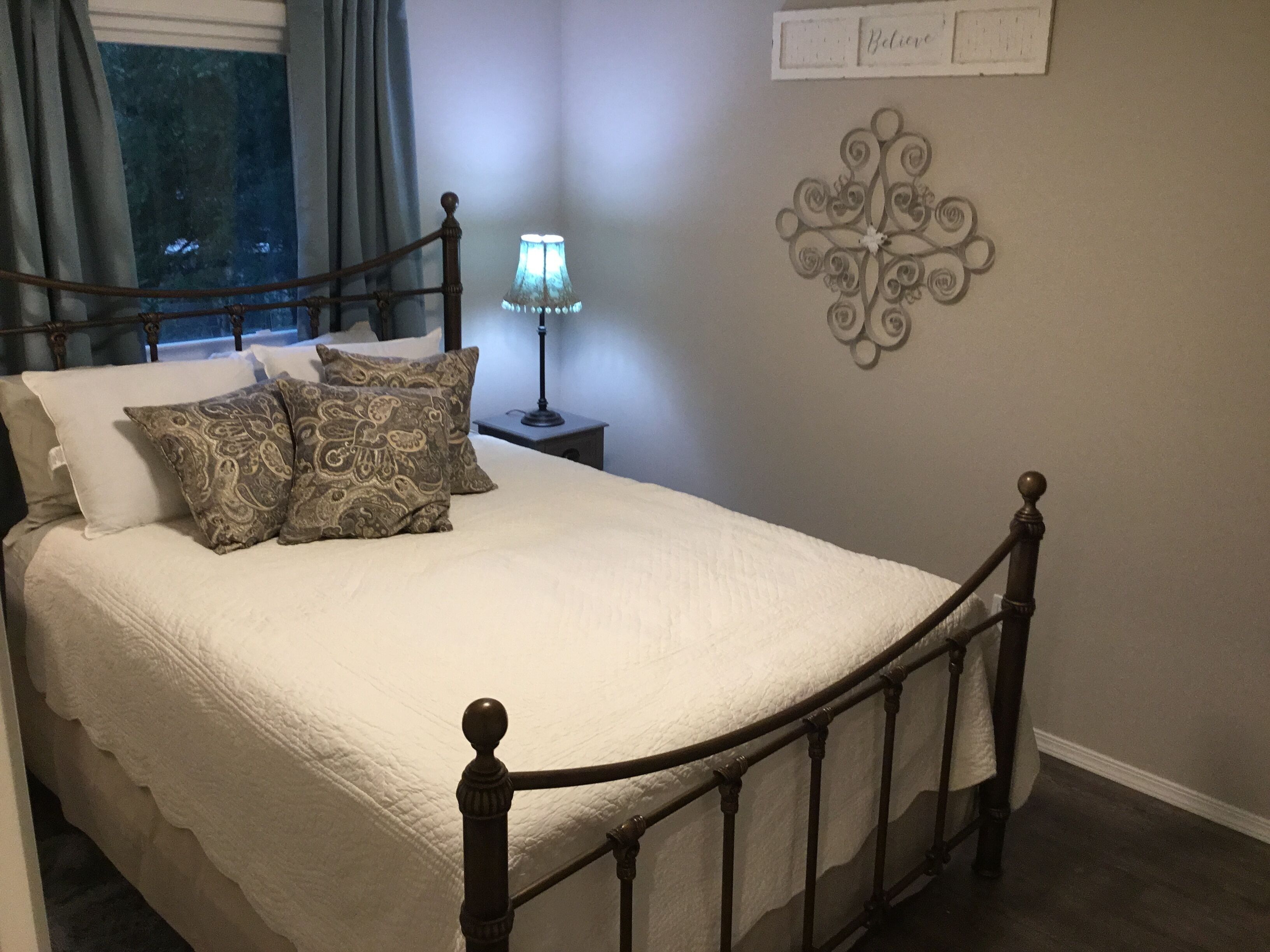 A neatly made bed with a headboard, a bedside lamp, and decorative wall art.