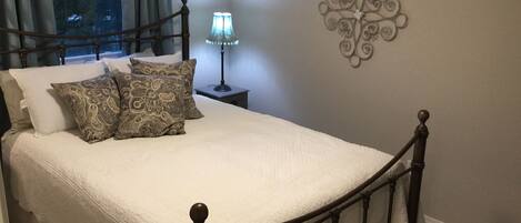 A neatly made bed with a headboard, a bedside lamp, and decorative wall art.