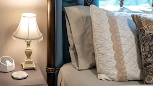 A neatly made bed with a quilted white and beige pillow, a decorative lamp, and a small white object on a bedside table. - Private House in Woodinville with Hot Tub, close to Wineries! (Woodinville)