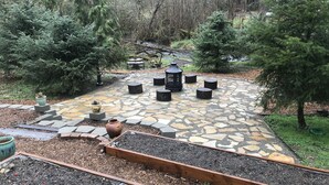 A stone patio with wooden planters, a wooden bench area, and a small garden bed. - Private House in Woodinville with Hot Tub, close to Wineries! (Woodinville)
