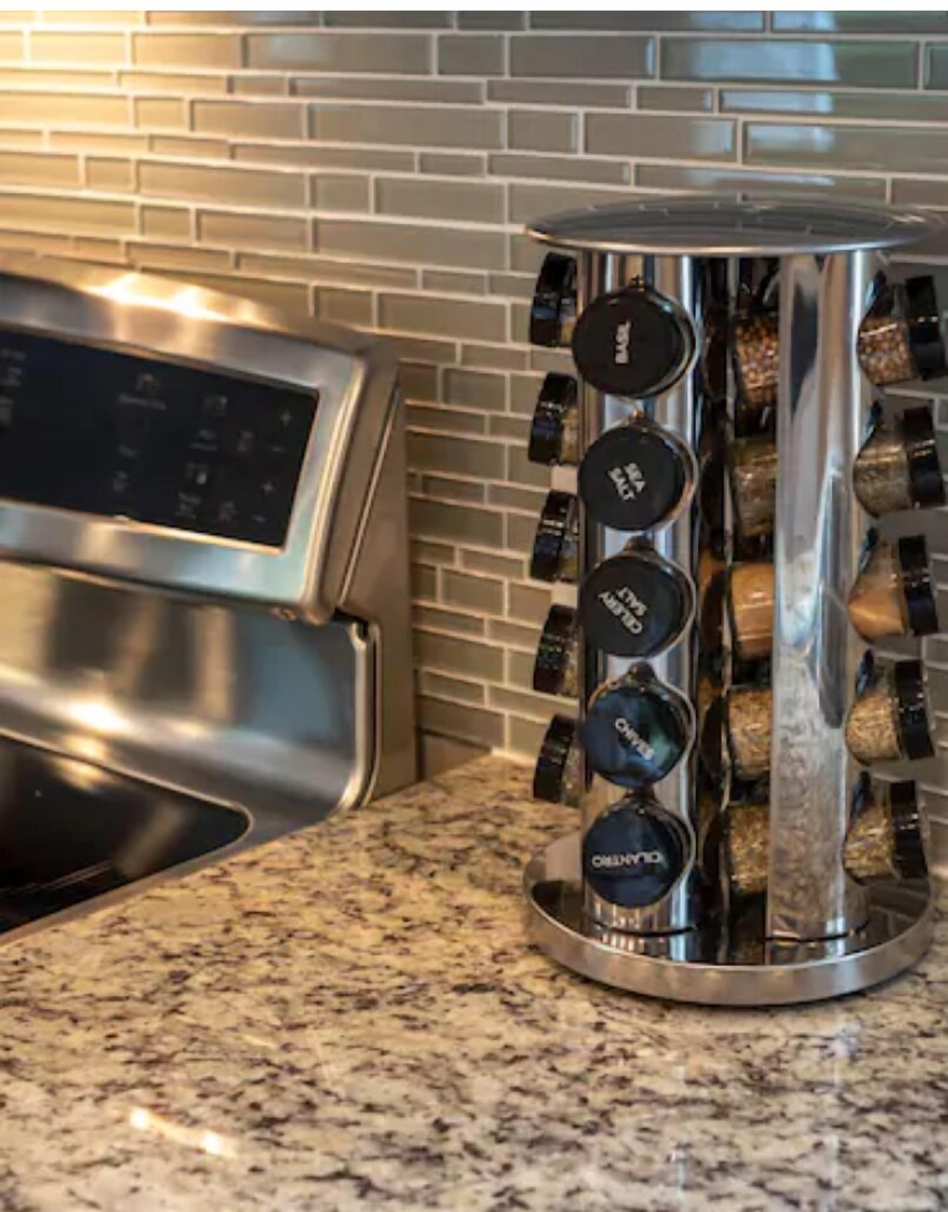 A kitchen with a stainless steel range hood and a spice rack with various spices.
