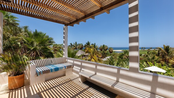 A balcony with a view of the beach, palm trees, and a wooden pergola. - Casa Mila - Ocean View Getaway (Todos Santos)