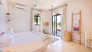 A bedroom with a bed, a window, a floor lamp, a hanging lantern, a woven basket, a wooden ladder, and a chair. - Casa Mila - Ocean View Getaway (Todos Santos)