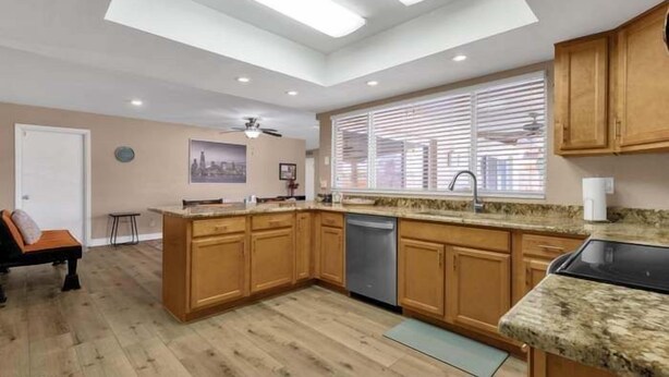 A modern kitchen with wooden cabinets, a dishwasher, and a granite countertop.