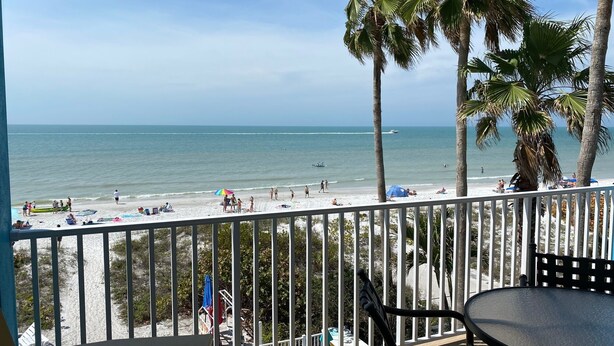 A balcony with a view of the beach, palm trees, and the ocean. - NEW Beachfront Condo, 2/2, Balcony, Heated Pool, INDIAN ROCKS BCH, Unit 303 (Indian Rocks Beach)