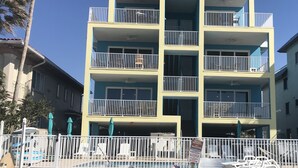 A multi-story hotel with balconies, a pool area, and a fenced beach section. - NEW Beachfront Condo, 2/2, Balcony, Heated Pool, INDIAN ROCKS BCH, Unit 303 (Indian Rocks Beach)