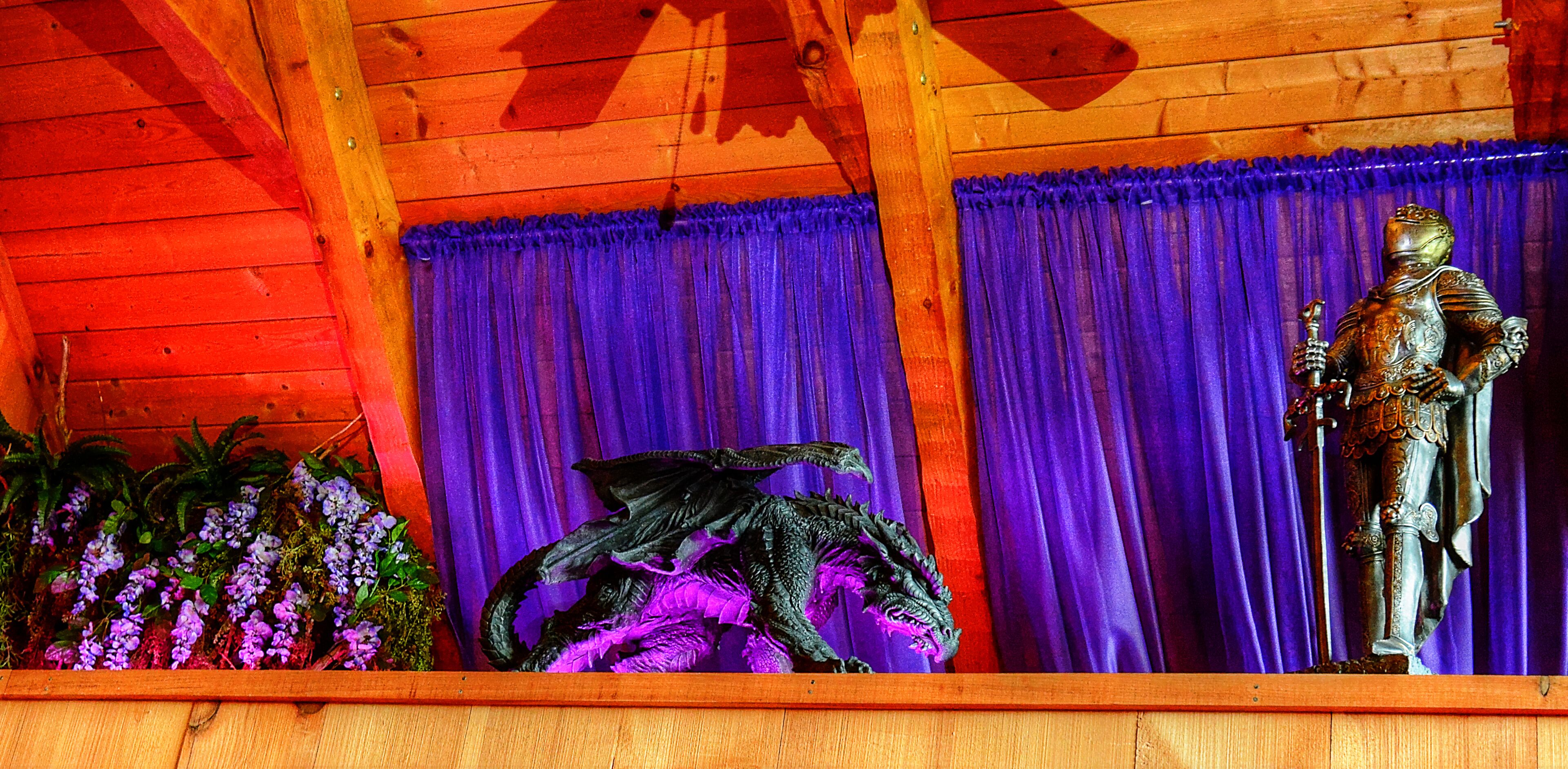 Un intérieur en bois agrémenté d’un rideau violet, d’une statue et d’une plante décorative.