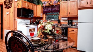 A wooden kitchen with a stove, microwave, and cabinets. There is a dining table with chairs and a vase of flowers. - OPEN 10/25-30, 11/8-11, 14-25 Knight of My Dreams,Secluded,Amazing View, 1 level (Sevierville)