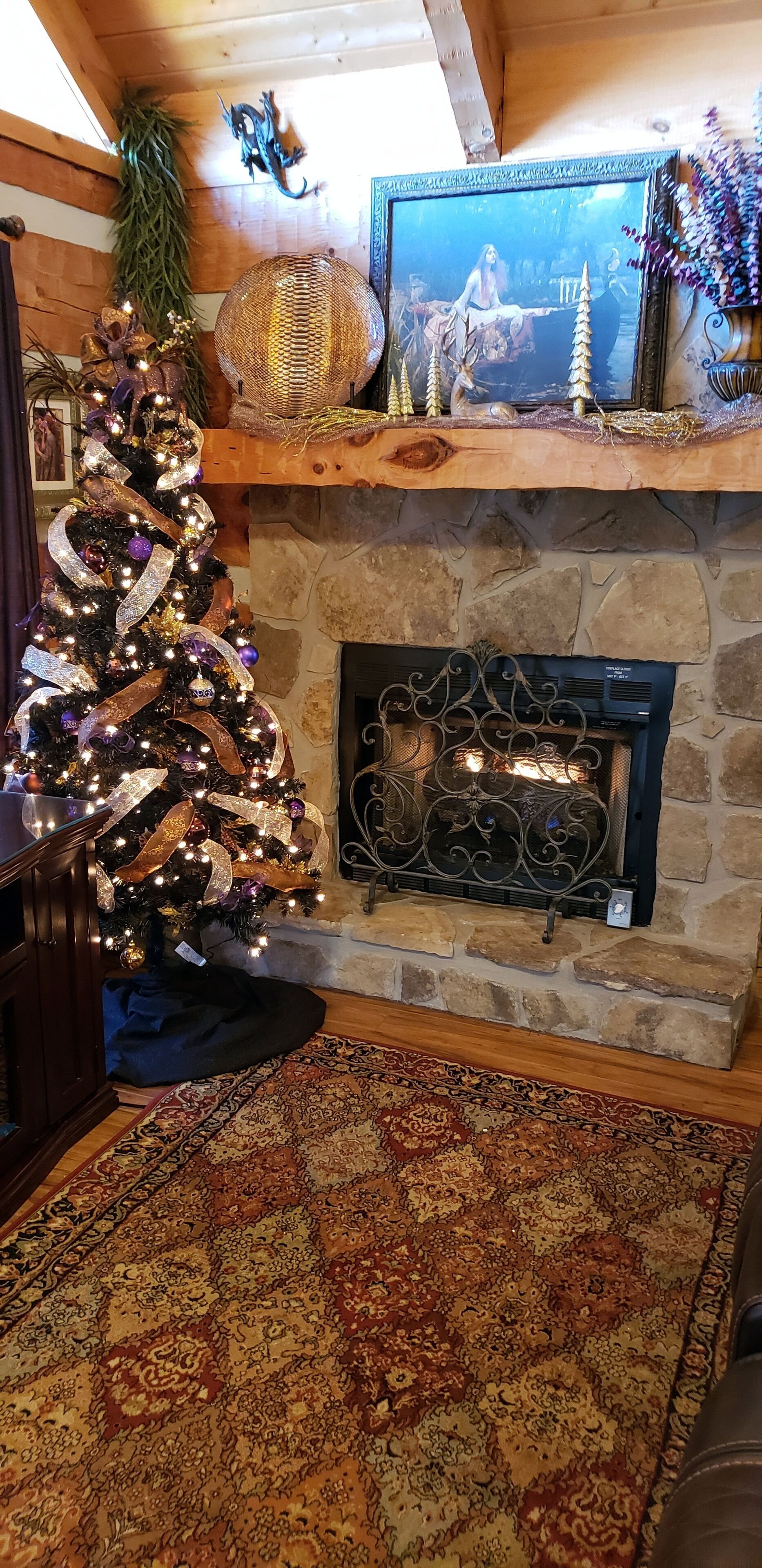 Una sala de estar acogedora con un árbol de Navidad decorado, una chimenea de piedra y una alfombra grande con estampado.