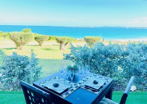 Mesa para dos con vistas al mar y un área verde con árboles.