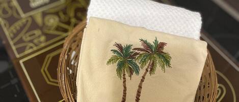 A woven basket with a white napkin featuring embroidered palm trees, placed on a table with a geometric patterned table runner.