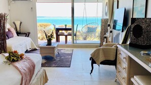 Een slaapkamer met een bed, een bureau, een stoel, een televisie en uitzicht op de oceaan.