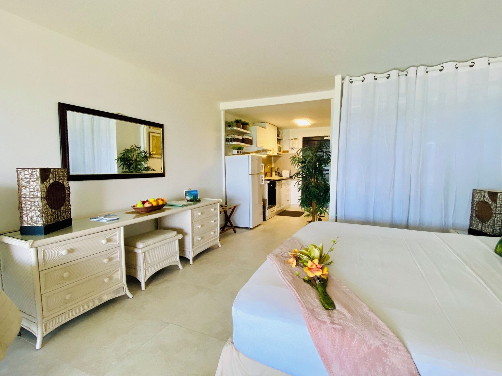 A hotel room with a bed, a desk, a dresser, and a bathroom visible through an open door.