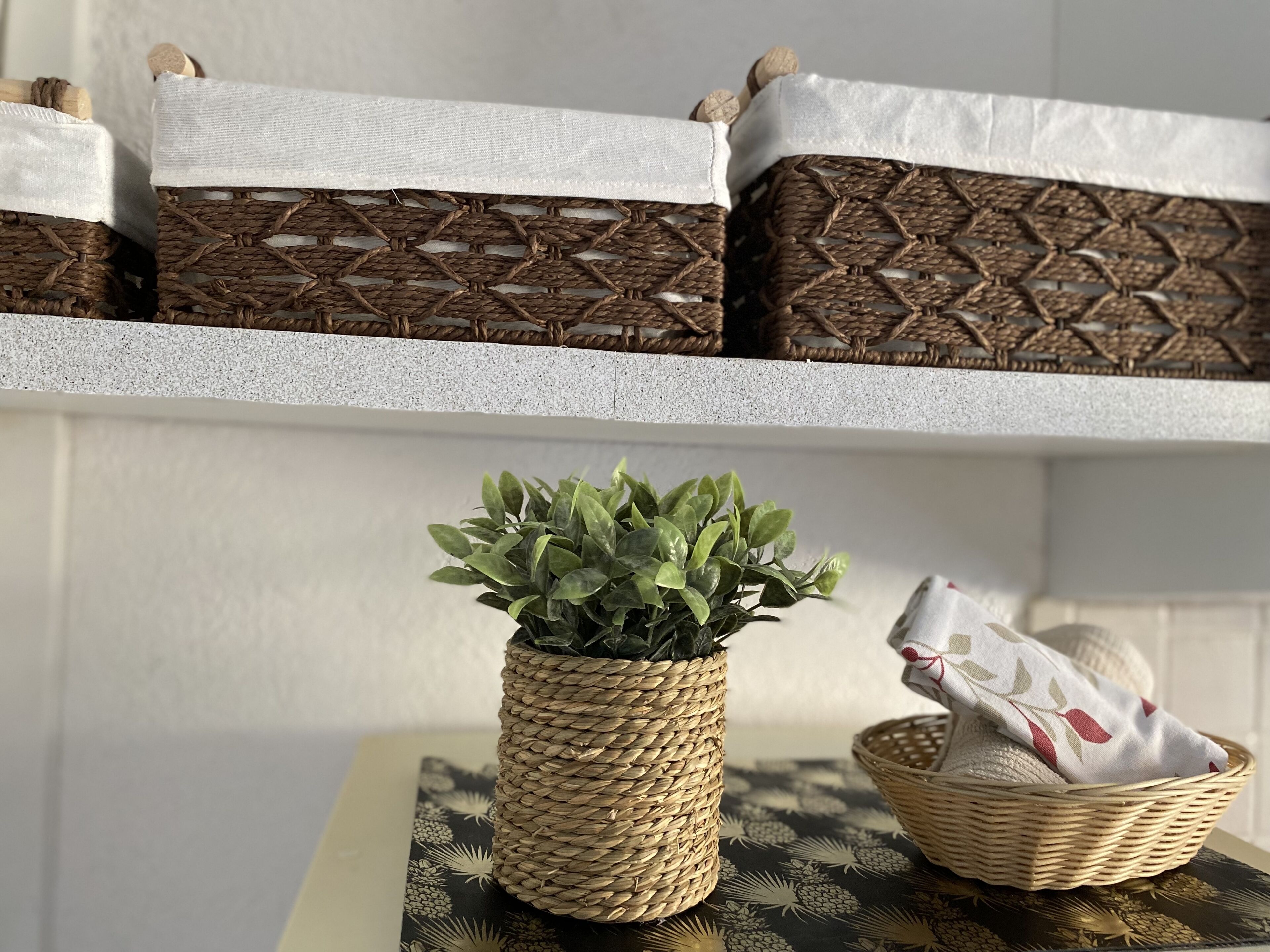 A room with a table displaying a potted plant, a basket, and a decorative pillow.