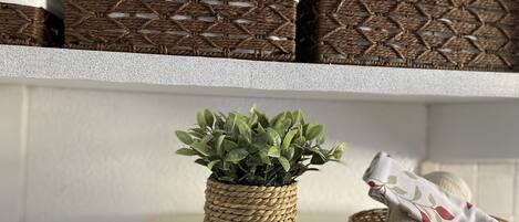 A room with a table displaying a potted plant, a basket, and a decorative pillow.